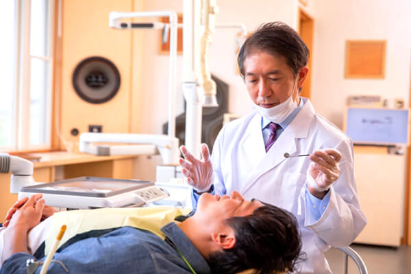 虫歯治療で歯科治療を行う歯科医と患者の写真